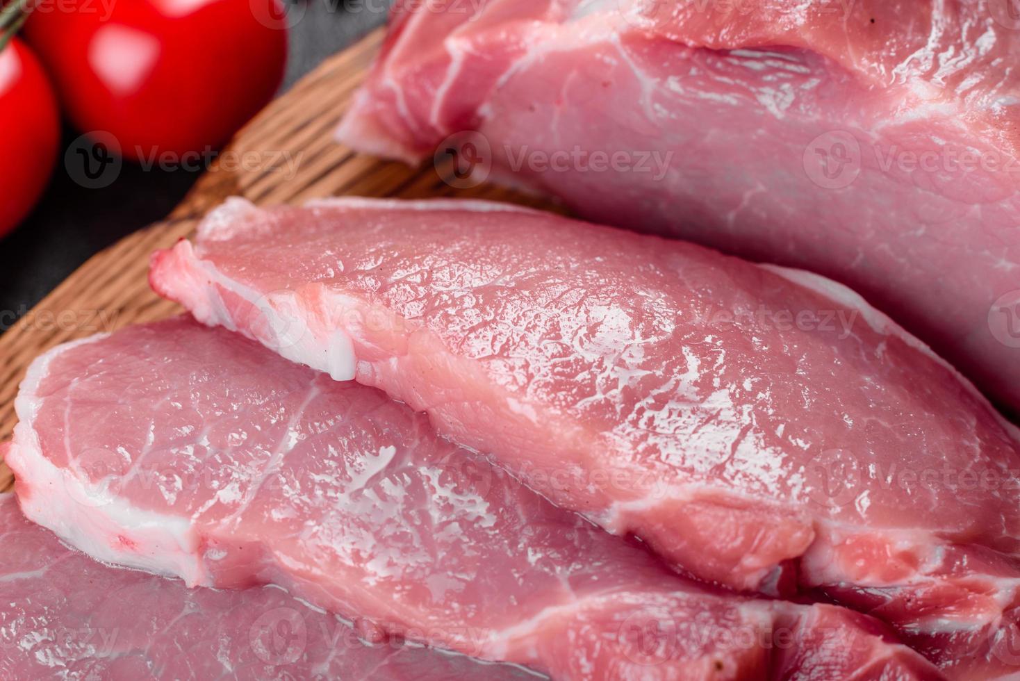 pezzi di maiale freschi pronti da cucinare su uno sfondo scuro in cucina foto