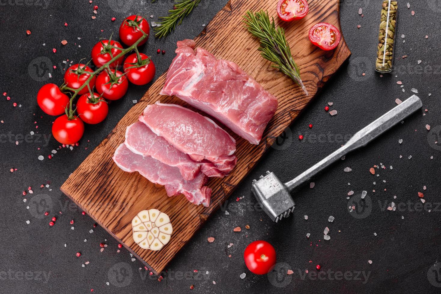 pezzi di maiale freschi pronti da cucinare su uno sfondo scuro in cucina foto