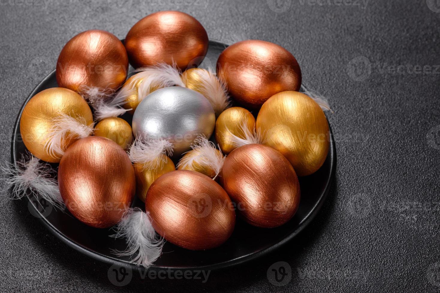 uova di pasqua oro e bronzo e torta di pasqua su sfondo scuro foto