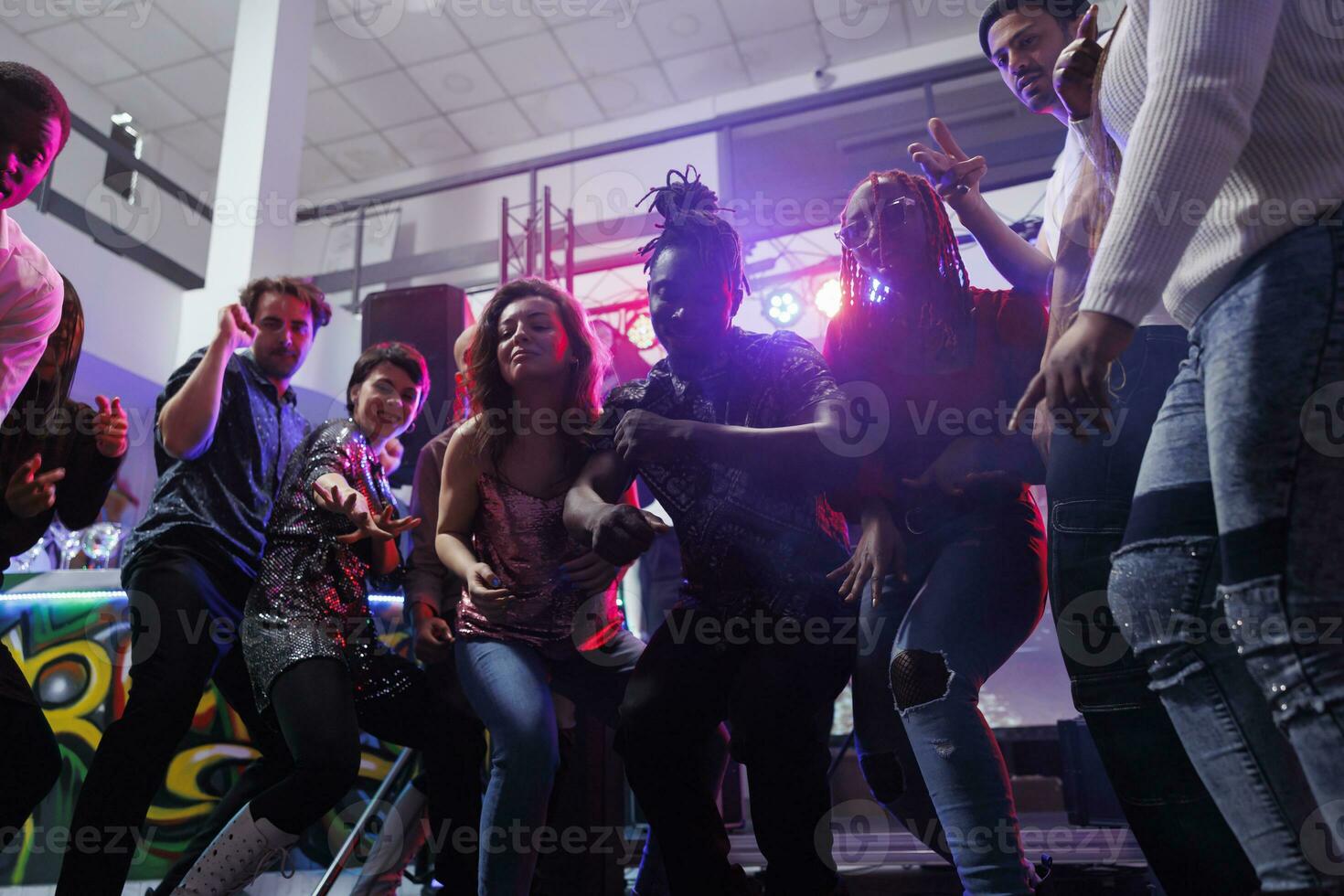 giovane persone danza e salto insieme su pista da ballo nel discoteca. diverso uomini e donne amici partying e discoteca a club festa mentre godendo vita notturna divertimento foto