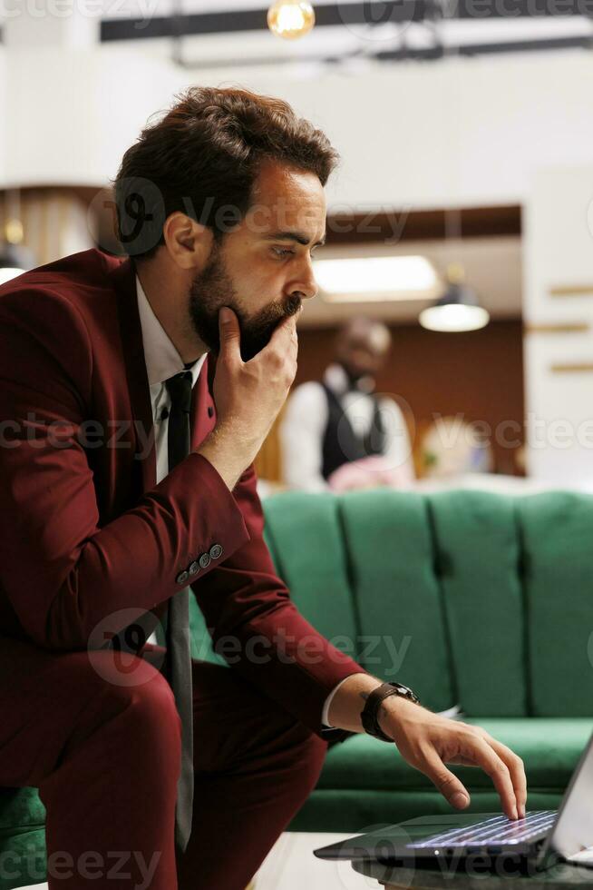 uomo d'affari in viaggio su opera viaggio e rivedere azienda Appunti per presente a ufficiale conferenza a livello internazionale. bianca collare lavoratore utilizzando il computer portatile nel Hotel sala la zona, collaborazione. foto