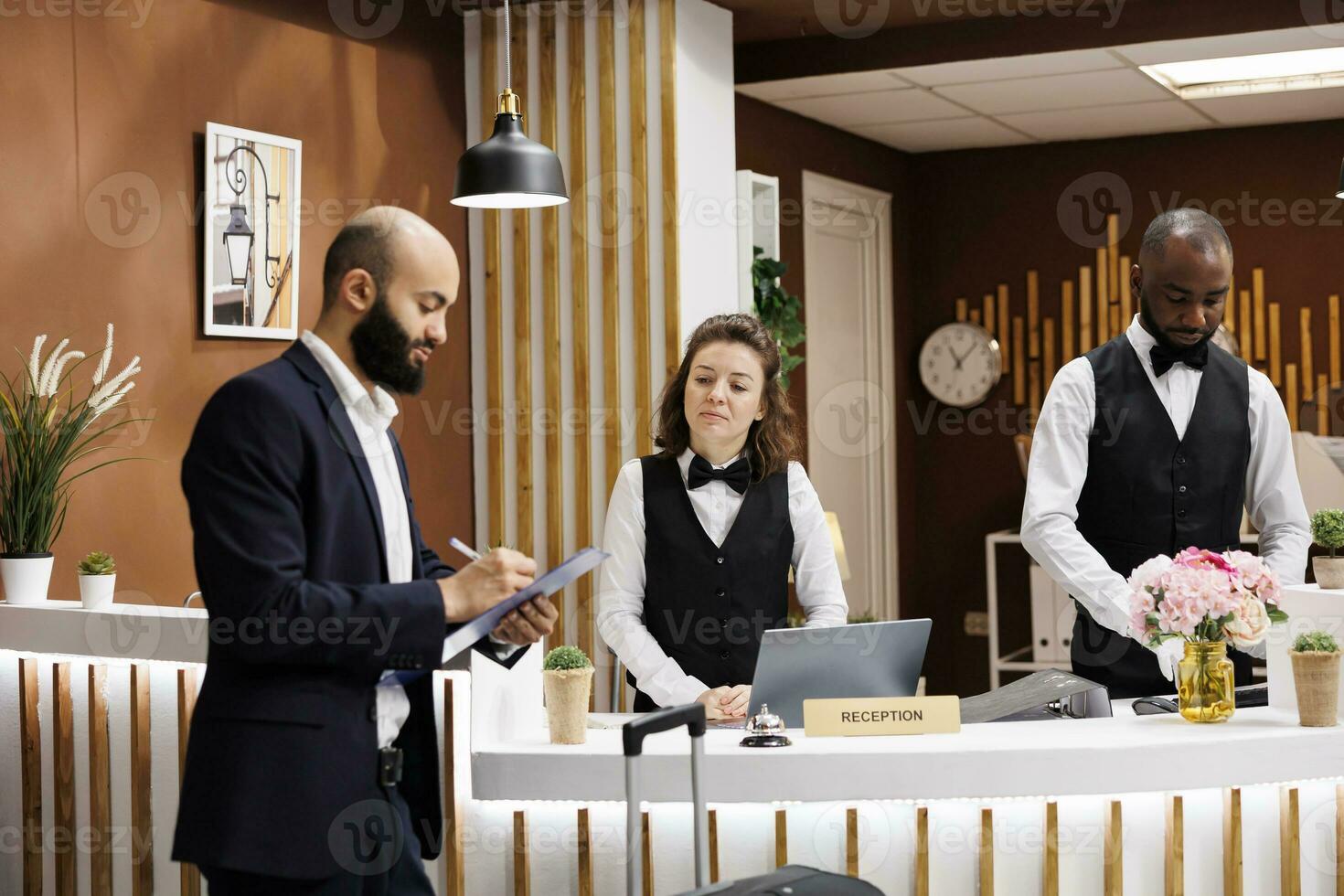 imprenditore arrivo nel Hotel ricezione, firma le forme per Registrati e dai un'occhiata in. professionale uomo con vestito formale e valigia soggiorno a lusso ricorrere per assistere importante attività commerciale incontri. foto