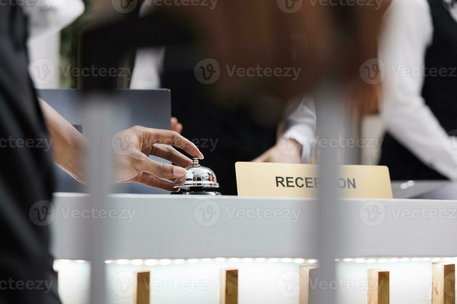 persona suono servizio campana a contatore, utilizzando campana per chiamata su Hotel addetto alla reception nel atrio per registrazione. giovane maschio ospite a davanti scrivania parlando per personale di lusso struttura ricettiva. vicino su. foto