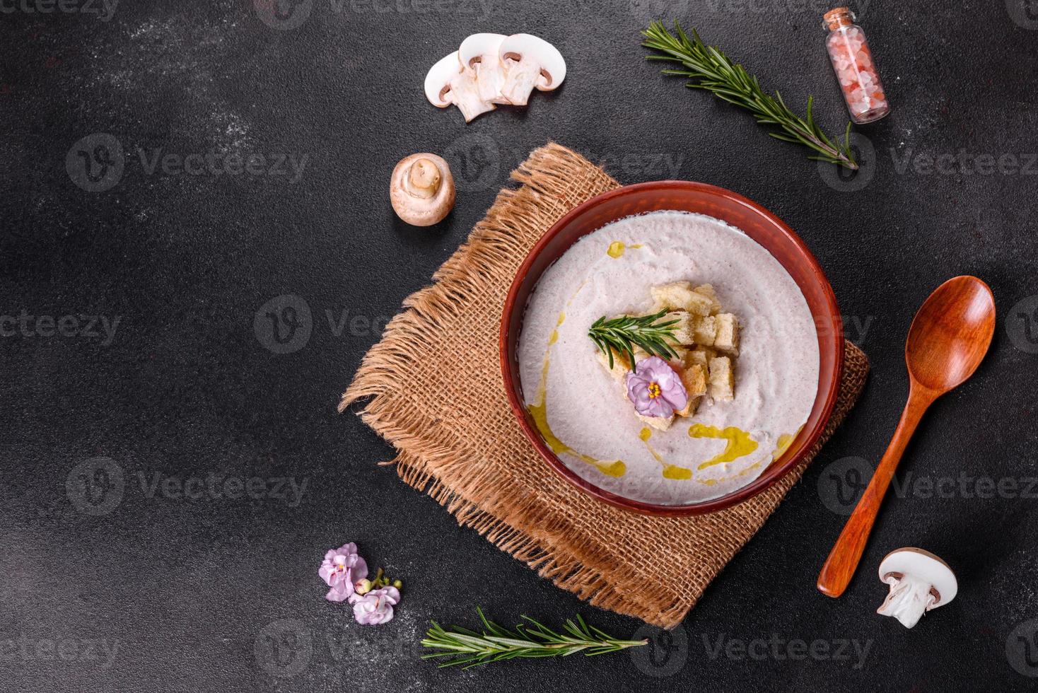 deliziosa zuppa di funghi in un piatto marrone con un cucchiaio di legno foto