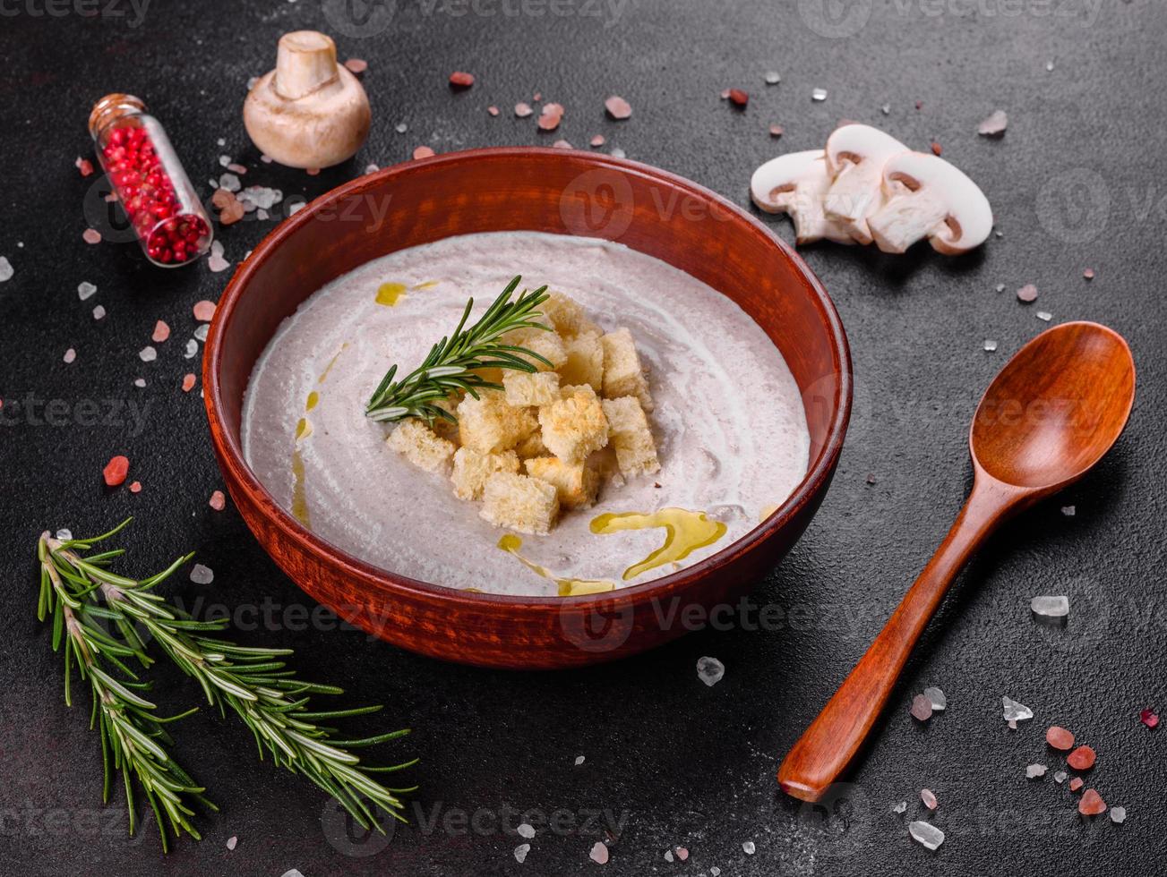 deliziosa zuppa di funghi in un piatto marrone con un cucchiaio di legno foto