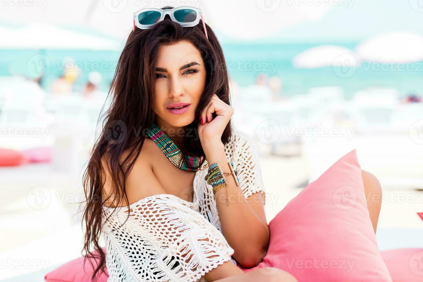estate ritratto di bellissimo brunetta donna chilling nel il spiaggia club. tropicale accessori. foto