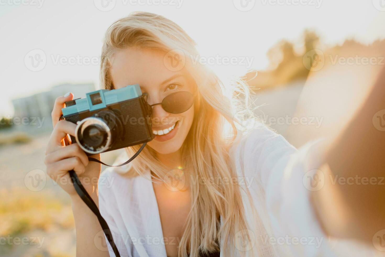 elegante formoso ragazza con retrò telecamera in posa su soleggiato spiaggia. la libertà e viaggio concetto. foto