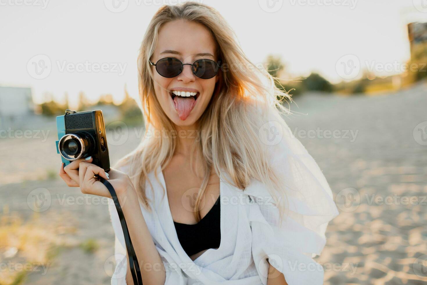 carino pulcino con retrò telecamera fabbricazione smorfie e in posa su il spiaggia. bellissimo luce del sole. foto