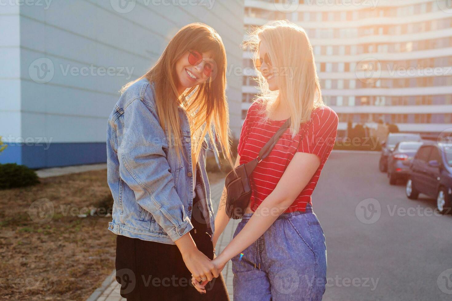 Due gioioso donne avendo divertimento all'aperto. elegante jeans giacca con Stampa. urbano sfondo . foto