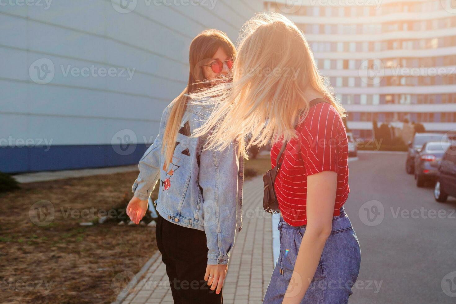 Due gioioso donne avendo divertimento all'aperto. elegante jeans giacca con Stampa. urbano sfondo . foto