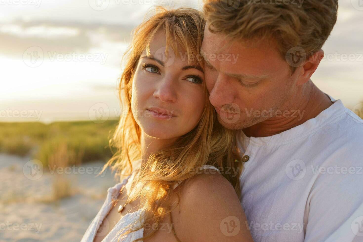 vicino su ritratto di sorprendente bellissimo coppia Abbracciare una persona contro tramonto mentre datazione. vicino su ritratto di uomo e donna insieme, guardare a ogni Altro. foto