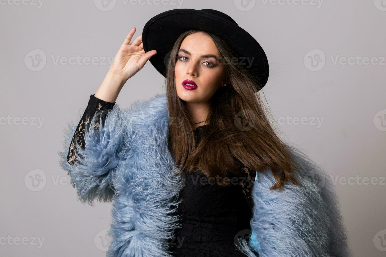 studio moda ritratto di bellissima donna nel elegante inverno soffice blu cappotto e nero cappello. foto