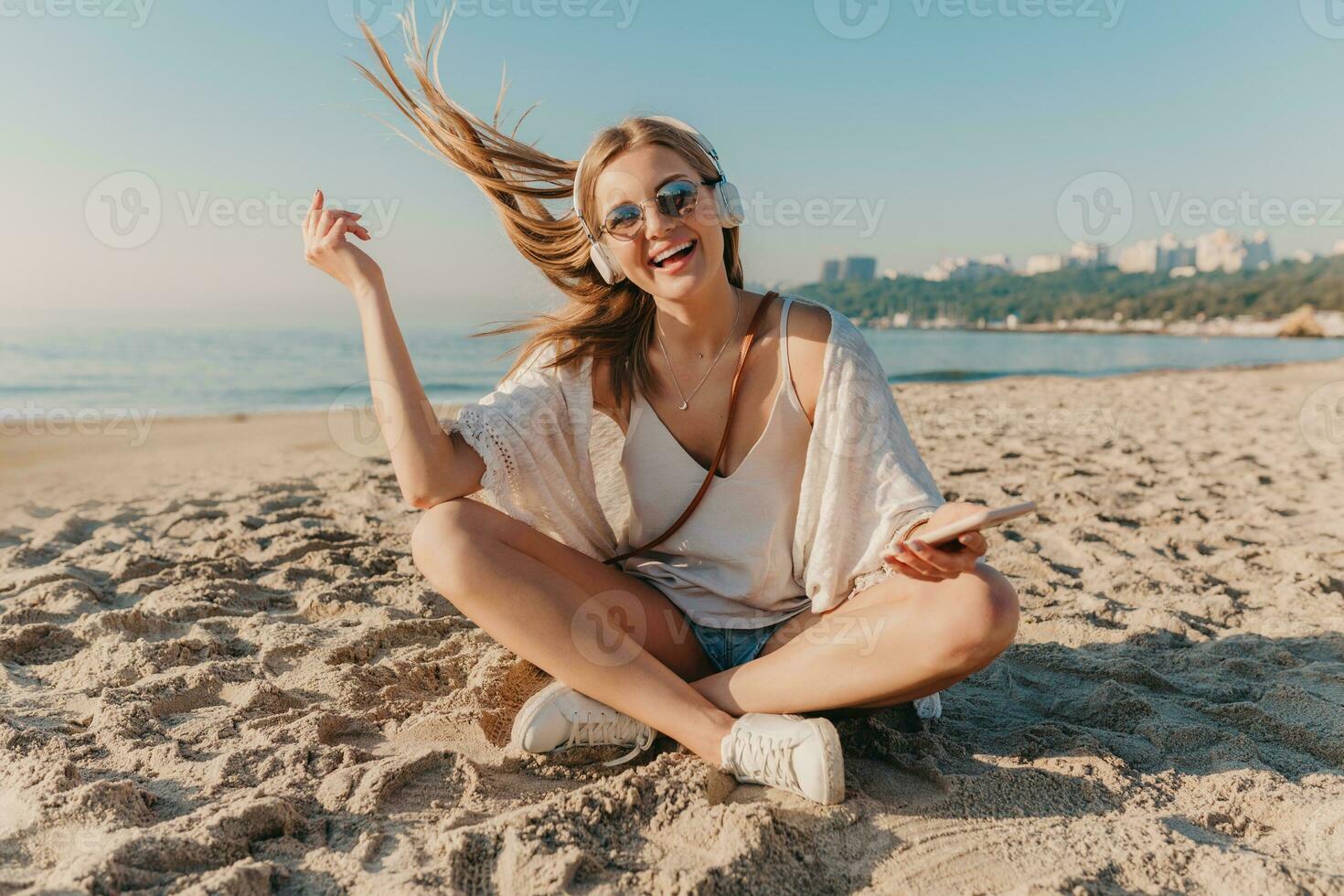 giovane attraente biondo sorridente donna su vacanza seduta su spiaggia foto