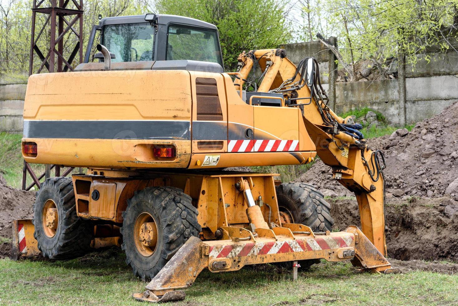 il moderno escavatore esegue lavori di scavo in cantiere foto