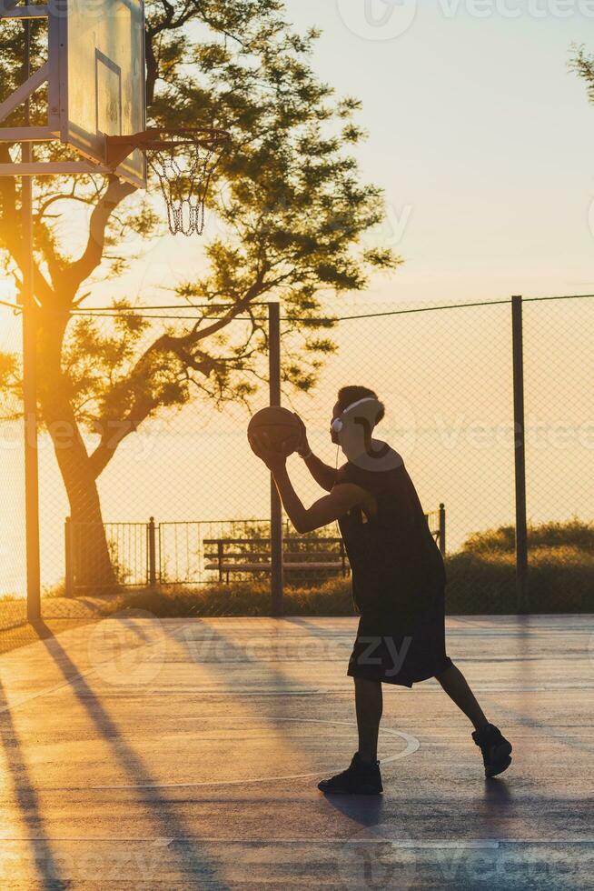 nero uomo fare gli sport, giocando pallacanestro su Alba, attivo stile di vita, soleggiato estate mattina foto