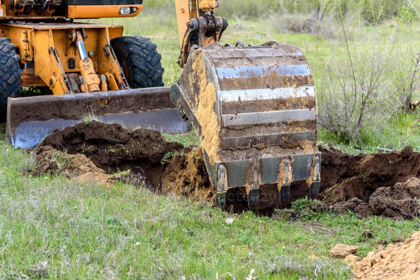 il moderno escavatore esegue lavori di scavo in cantiere foto