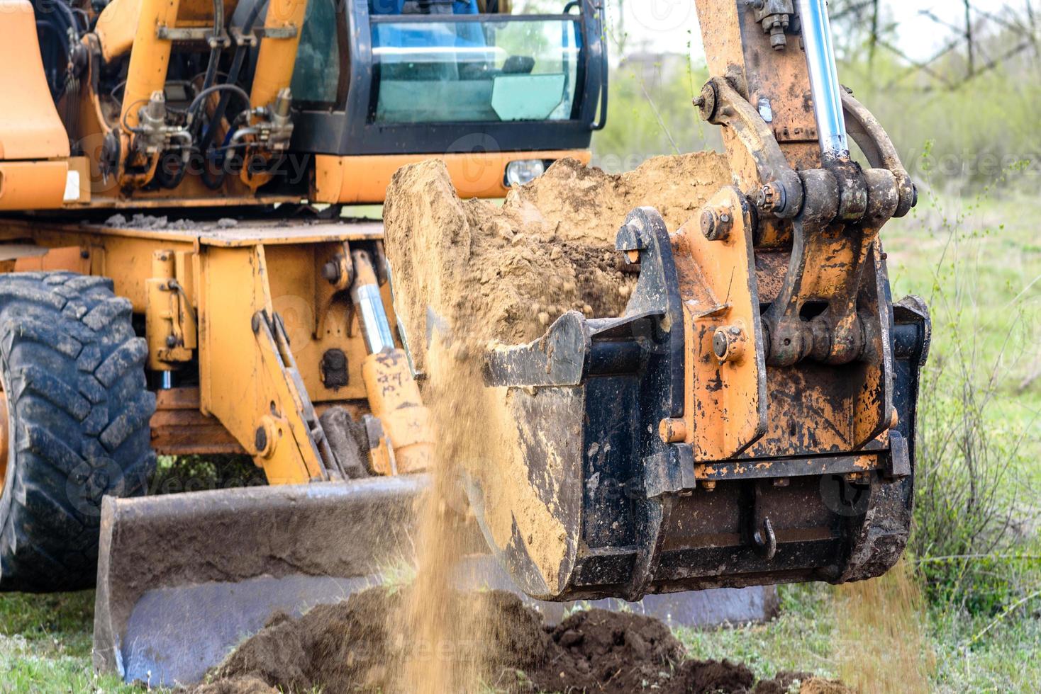 il moderno escavatore esegue lavori di scavo in cantiere foto