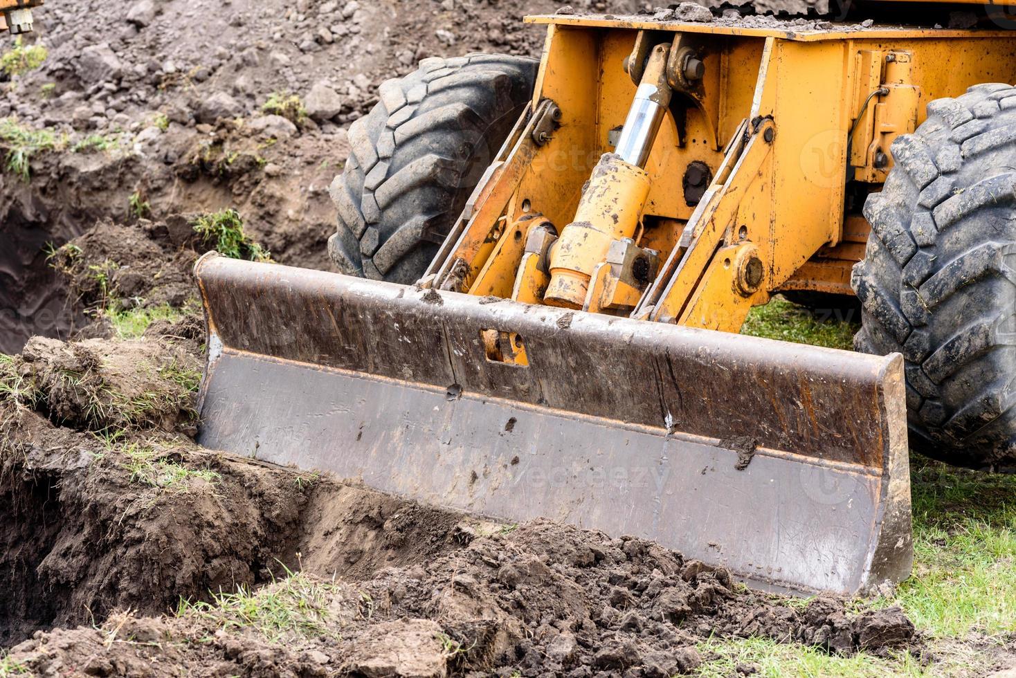 il moderno escavatore esegue lavori di scavo in cantiere foto