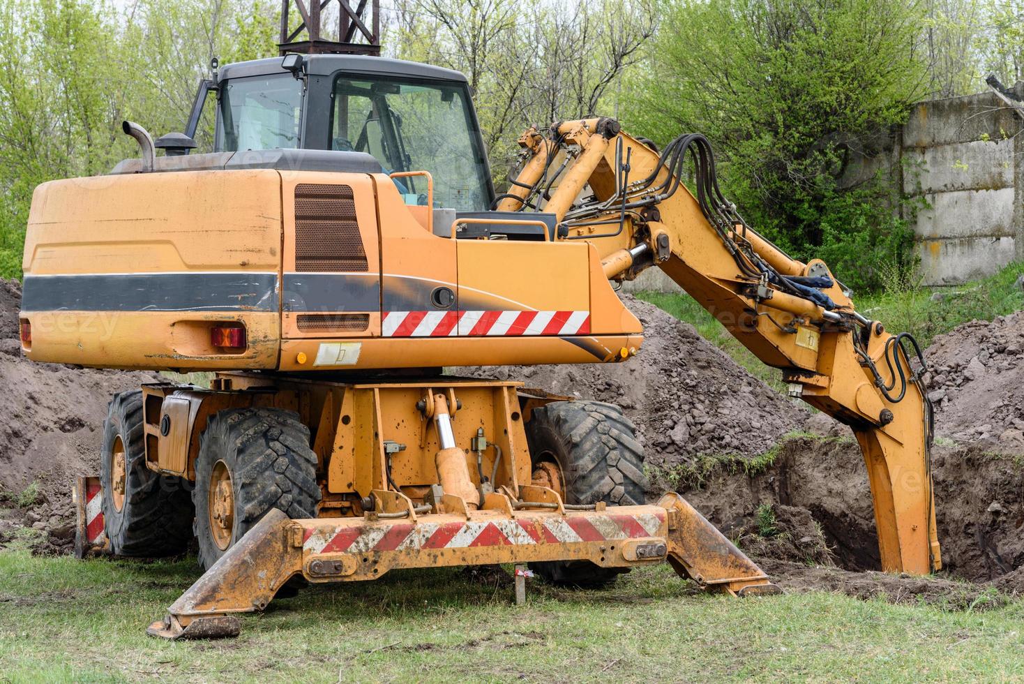 il moderno escavatore esegue lavori di scavo in cantiere foto