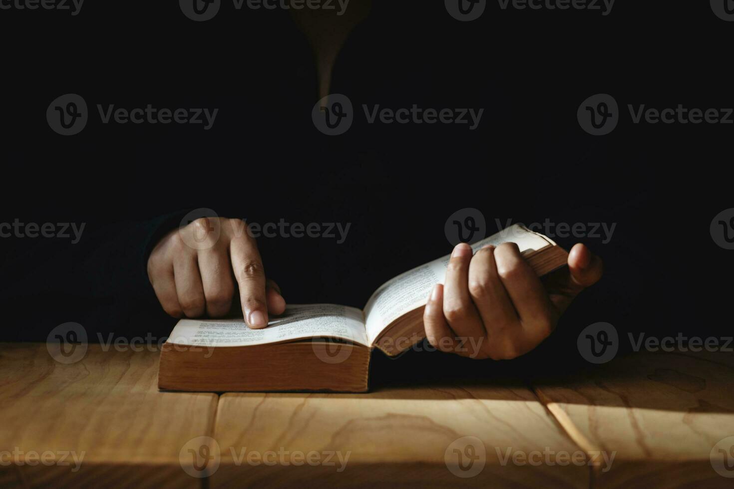 spiritualità, religione e speranza concetto. persona preghiere di lettura santo Bibbia su scrivania. simbolo di umiltà, supplica, credere e fede per cristiano le persone. buio tono. foto