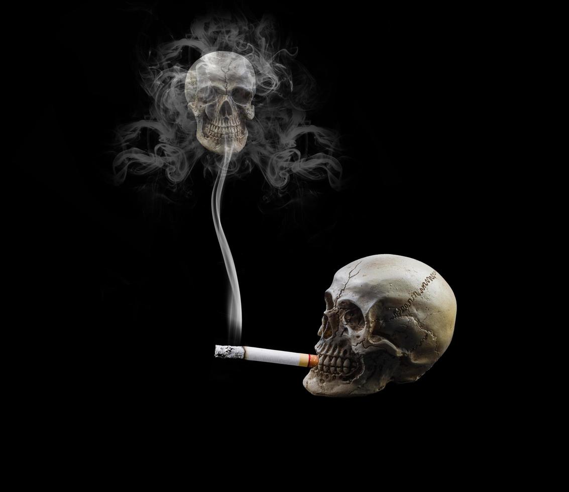 cranio umano che fuma una sigaretta su sfondo nero. foto
