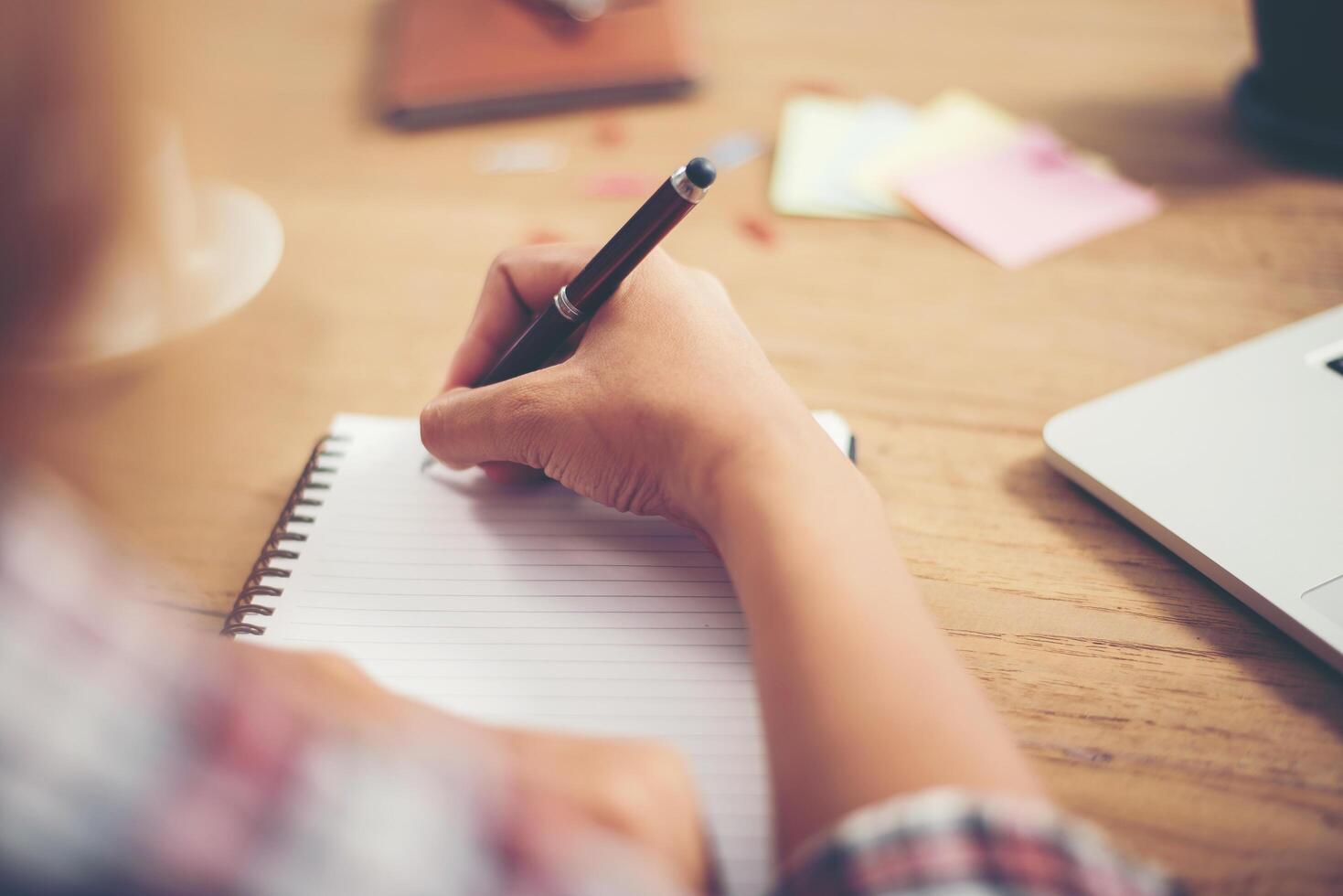 giovane donna hipster che scrive e lavora sul posto di lavoro. foto