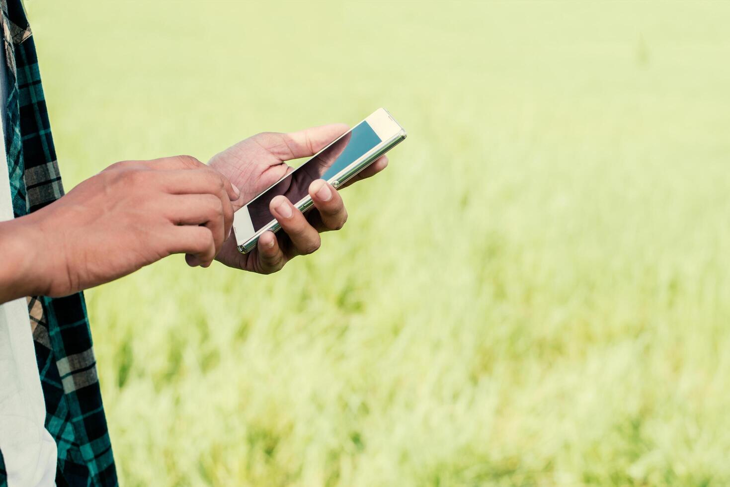 primo piano delle mani dell'uomo usando il suo smartphone all'aperto nel parco. foto