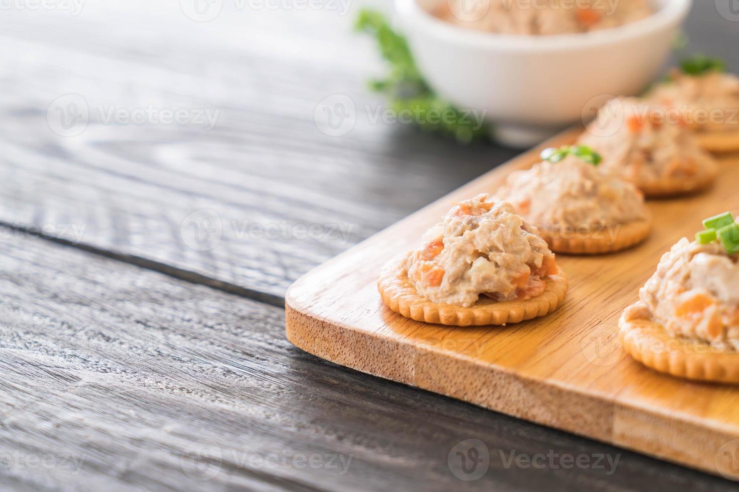 tonno spalmato con cracker su tavola di legno foto