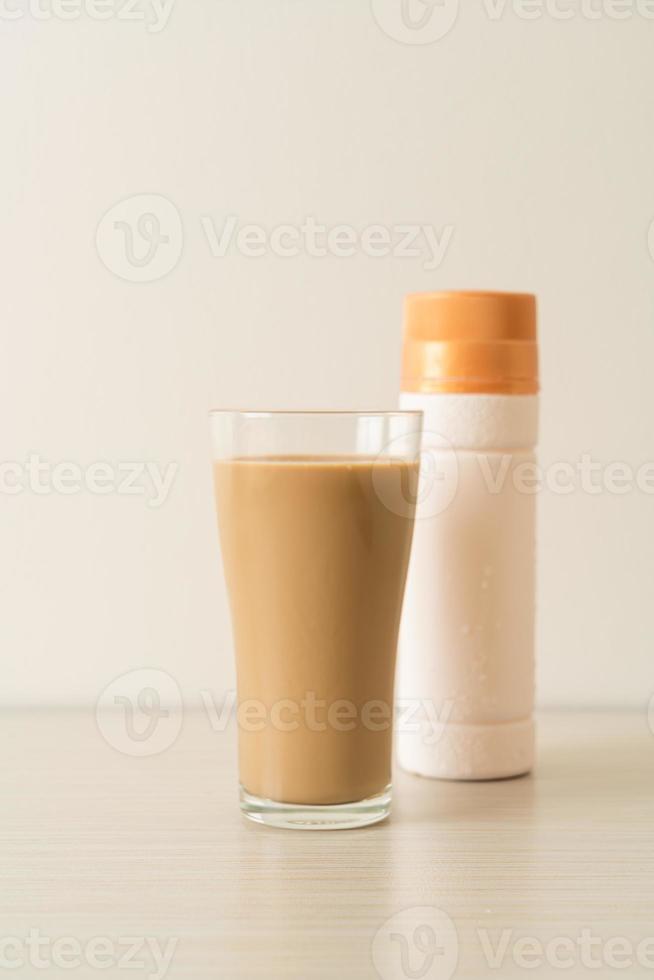 bicchiere di caffè latte con bottiglie di caffè pronte da bere sul tavolo foto