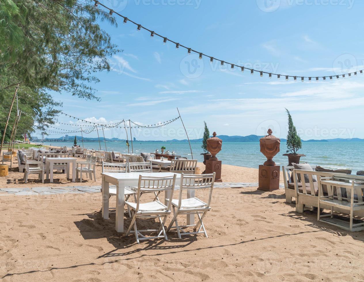 sedie bianche e tavolo sulla spiaggia con vista sull'oceano blu e cielo limpido: migliora lo stile di elaborazione del colore e dell'illuminazione foto