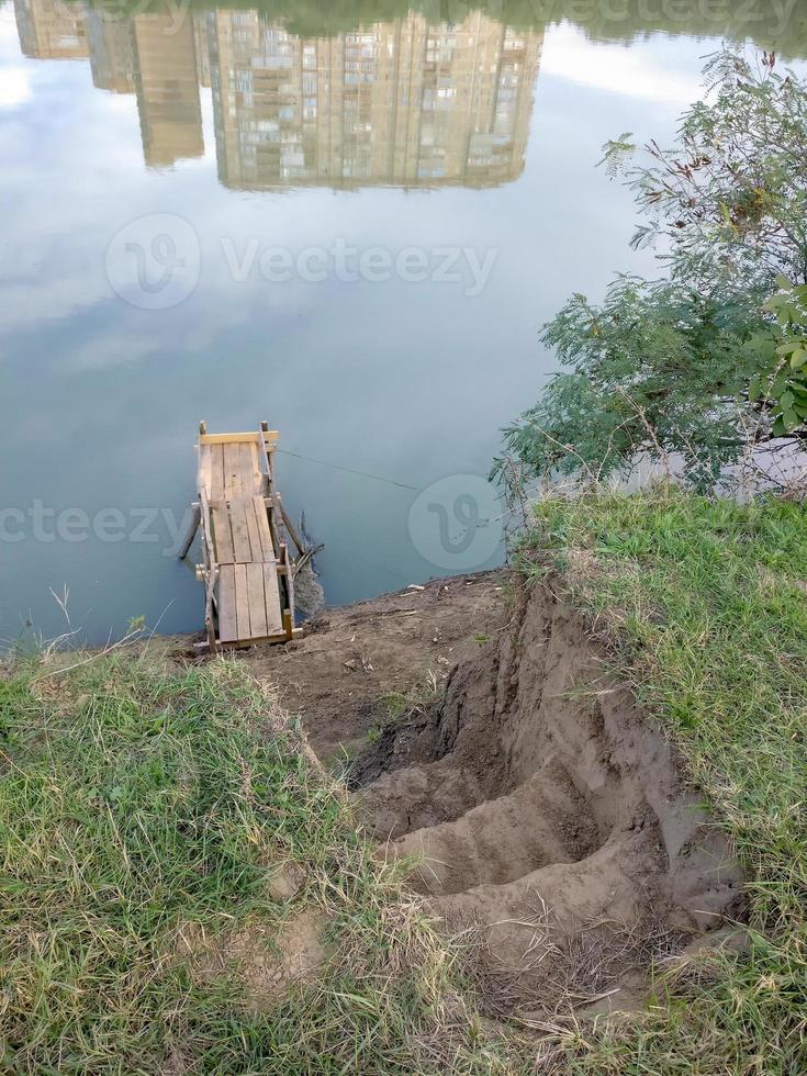 passi per il ponte di pini sul fiume e il riflesso delle case foto