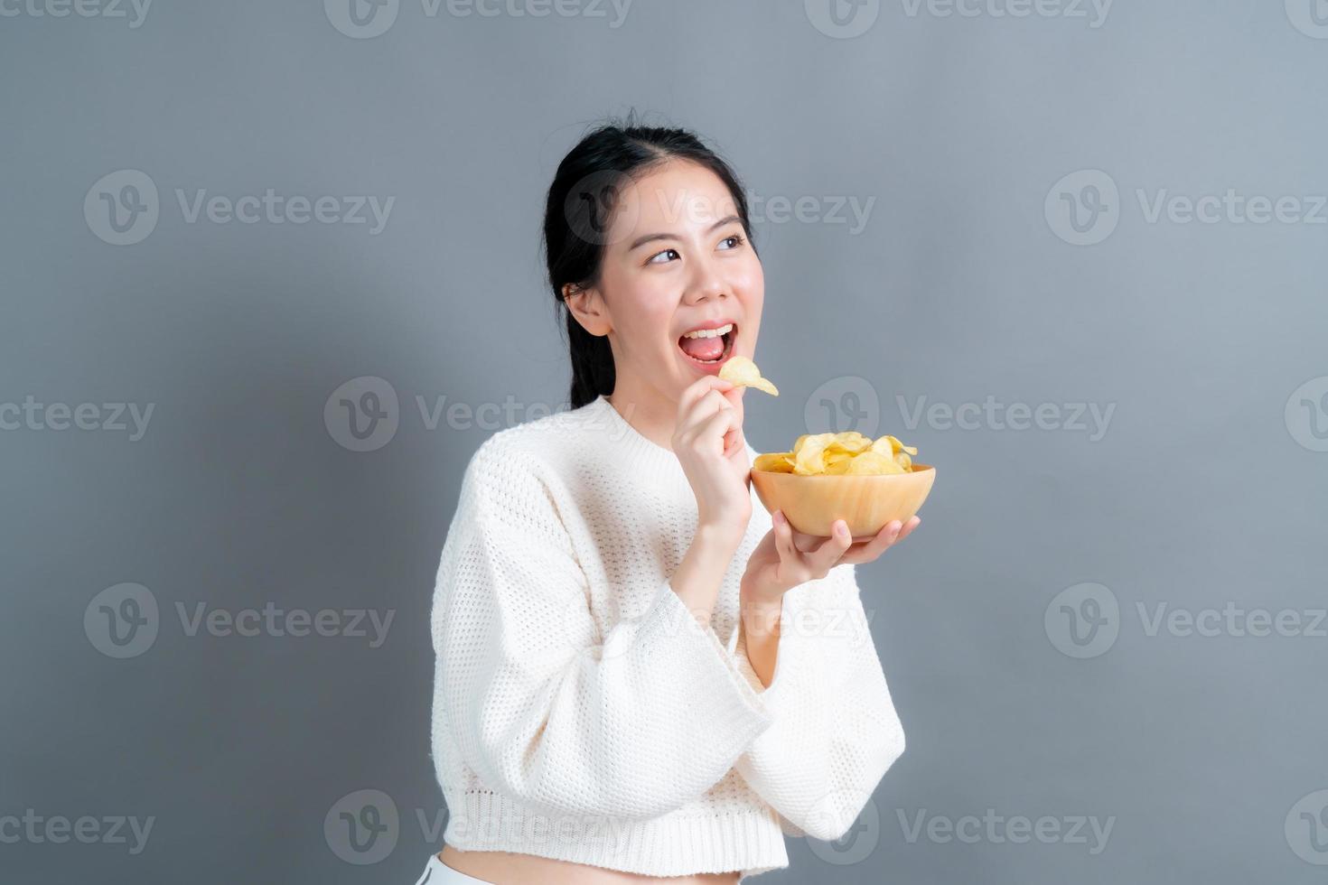 la giovane donna asiatica mangia le patatine fritte foto