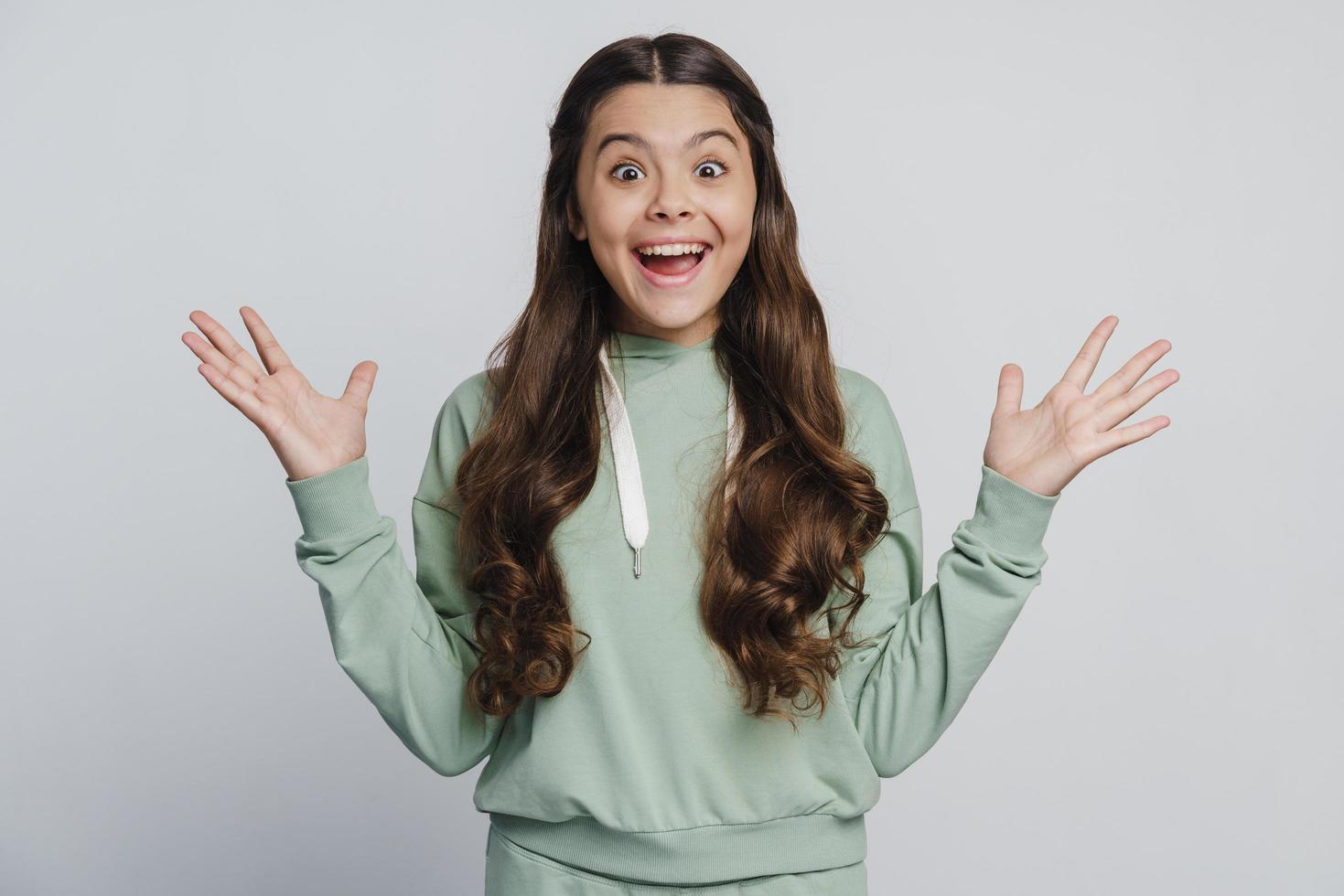 la ragazza felice e sorridente allarga le braccia, guarda la telecamera foto