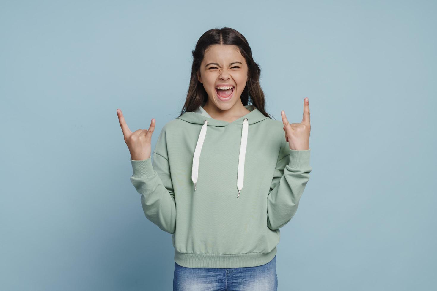 la ragazza allegra e sorridente mostra un gesto rock and roll foto