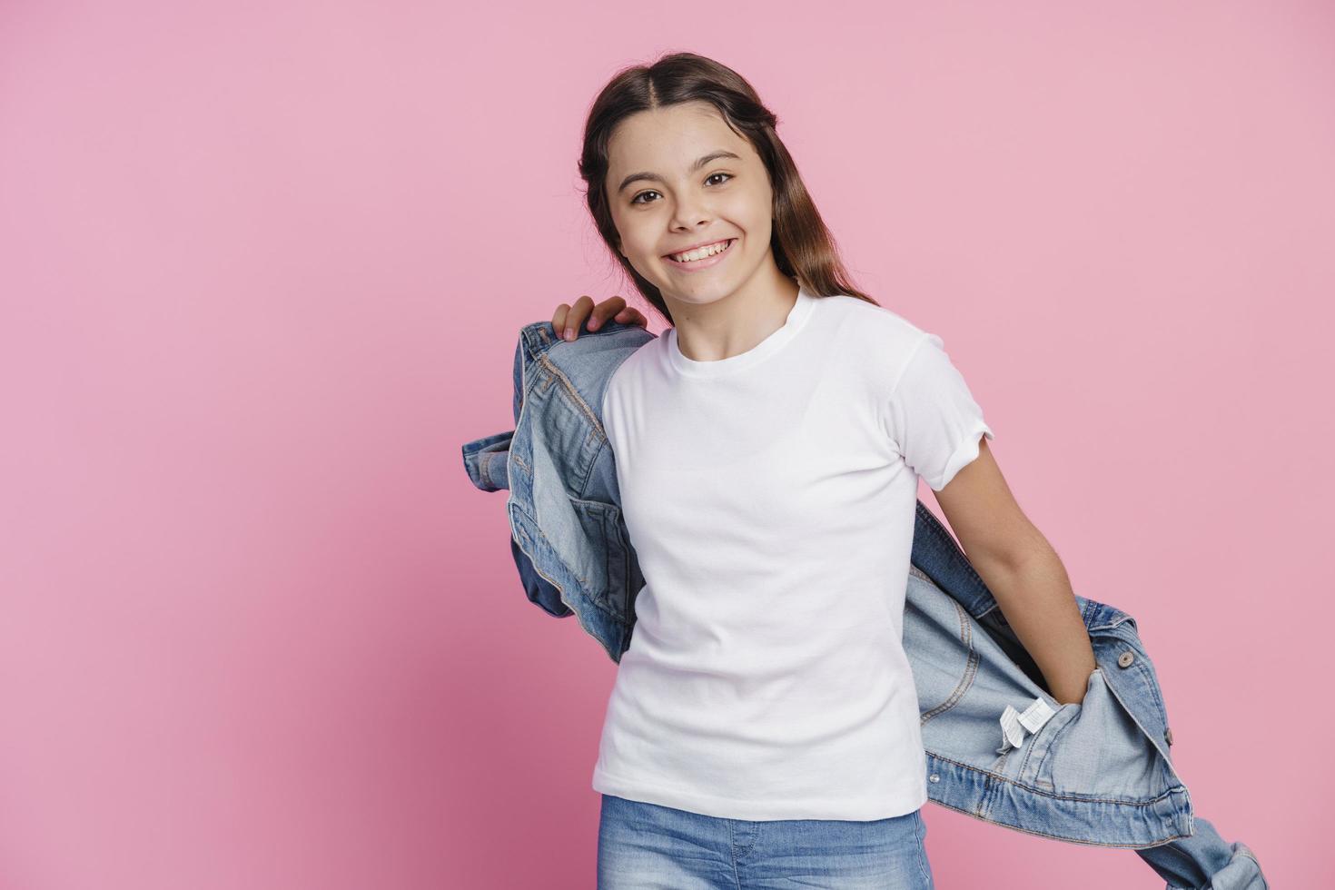 la ragazza positiva indossa una giacca di jeans su uno sfondo rosa foto