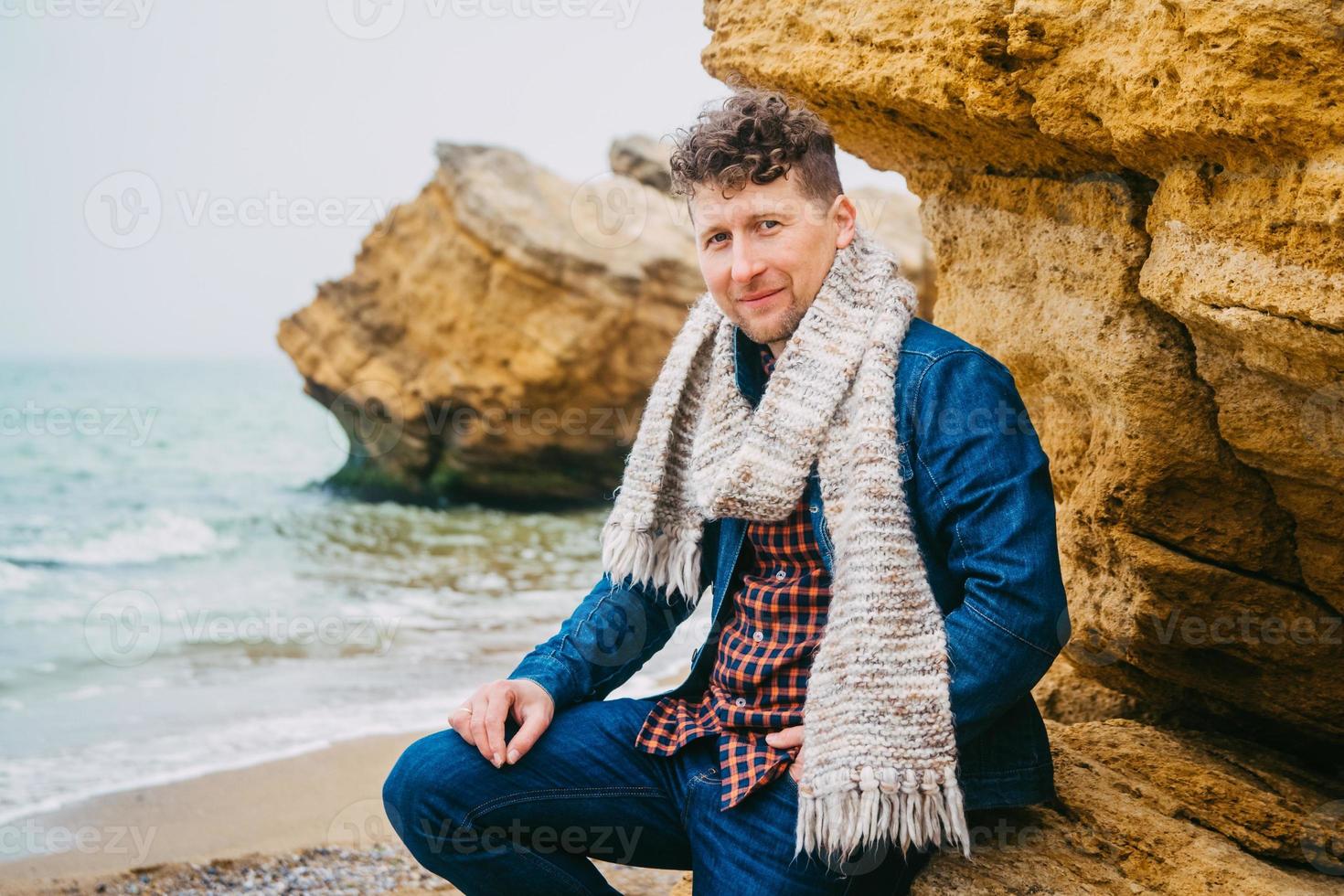 uomo viaggiatore vicino a una roccia contro un bellissimo mare con onde foto