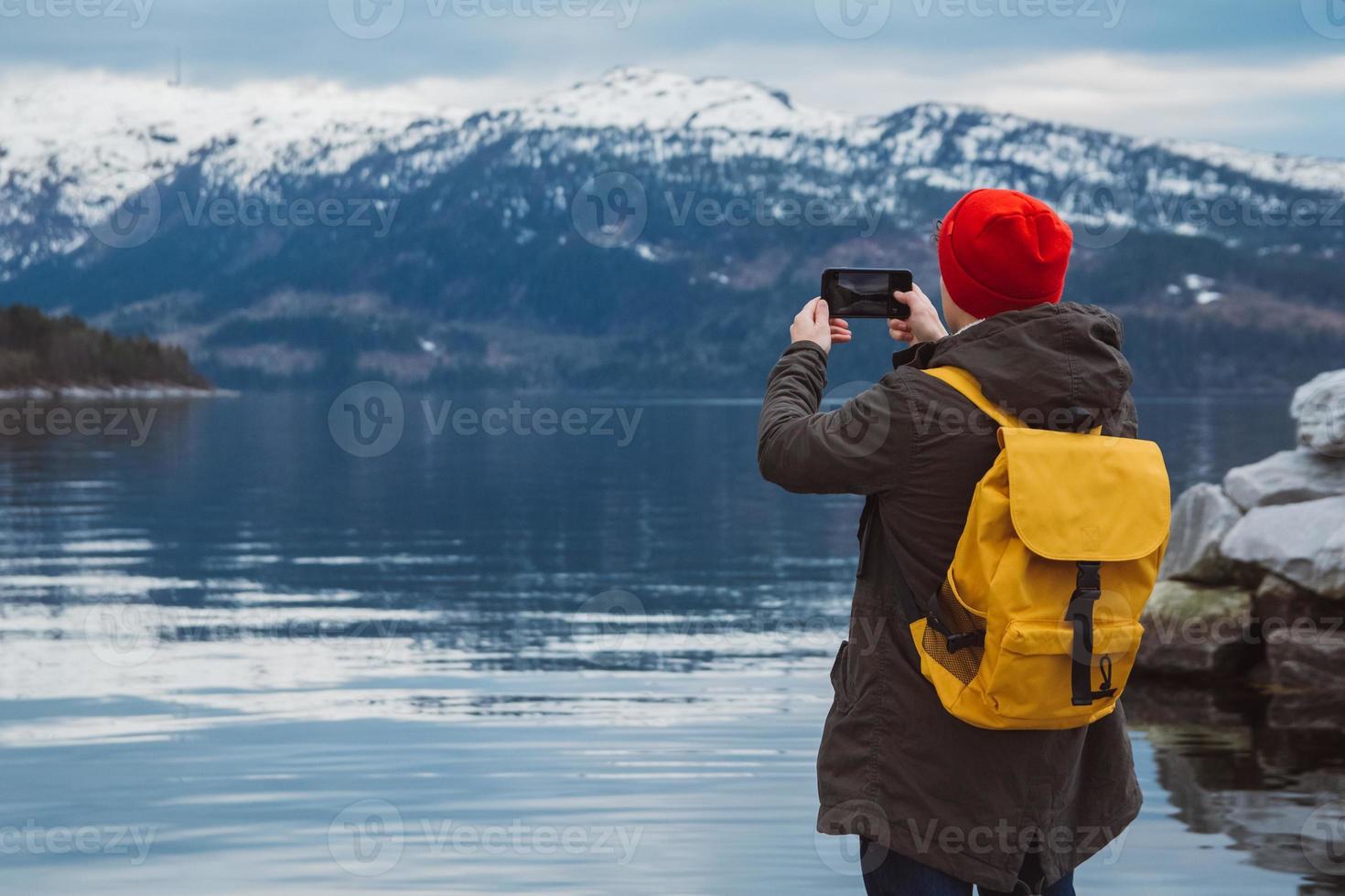 uomo viaggiatore che scatta foto con lo smartphone sulle montagne