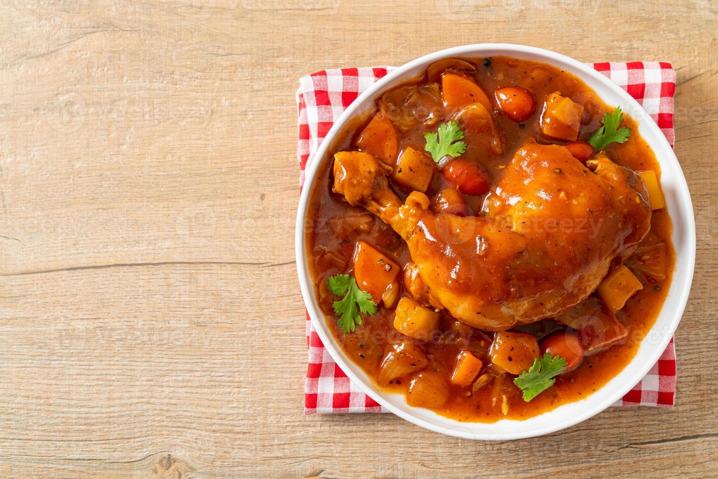 Spezzatino di pollo fatto in casa con pomodori, cipolle, carote e patate sul piatto foto