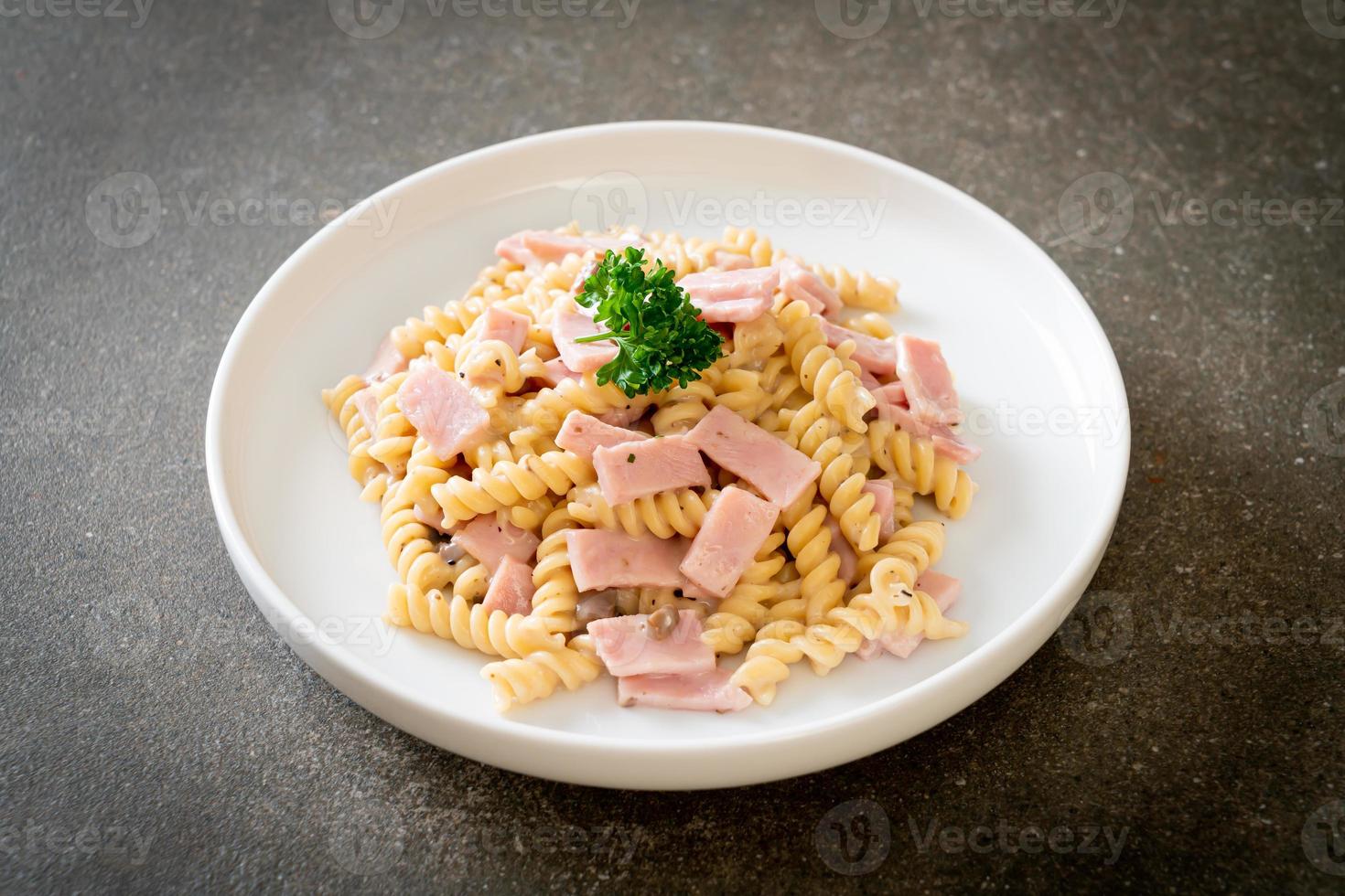 spirali o pasta a spirale salsa di crema di funghi con prosciutto - stile italiano foto