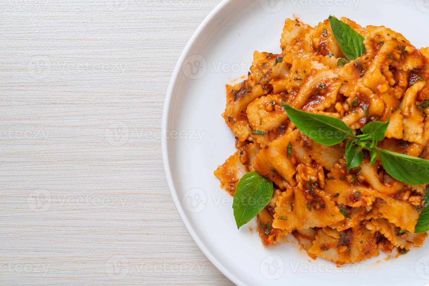 Farfalle con basilico e aglio in salsa di pomodoro - salsa italiana foto