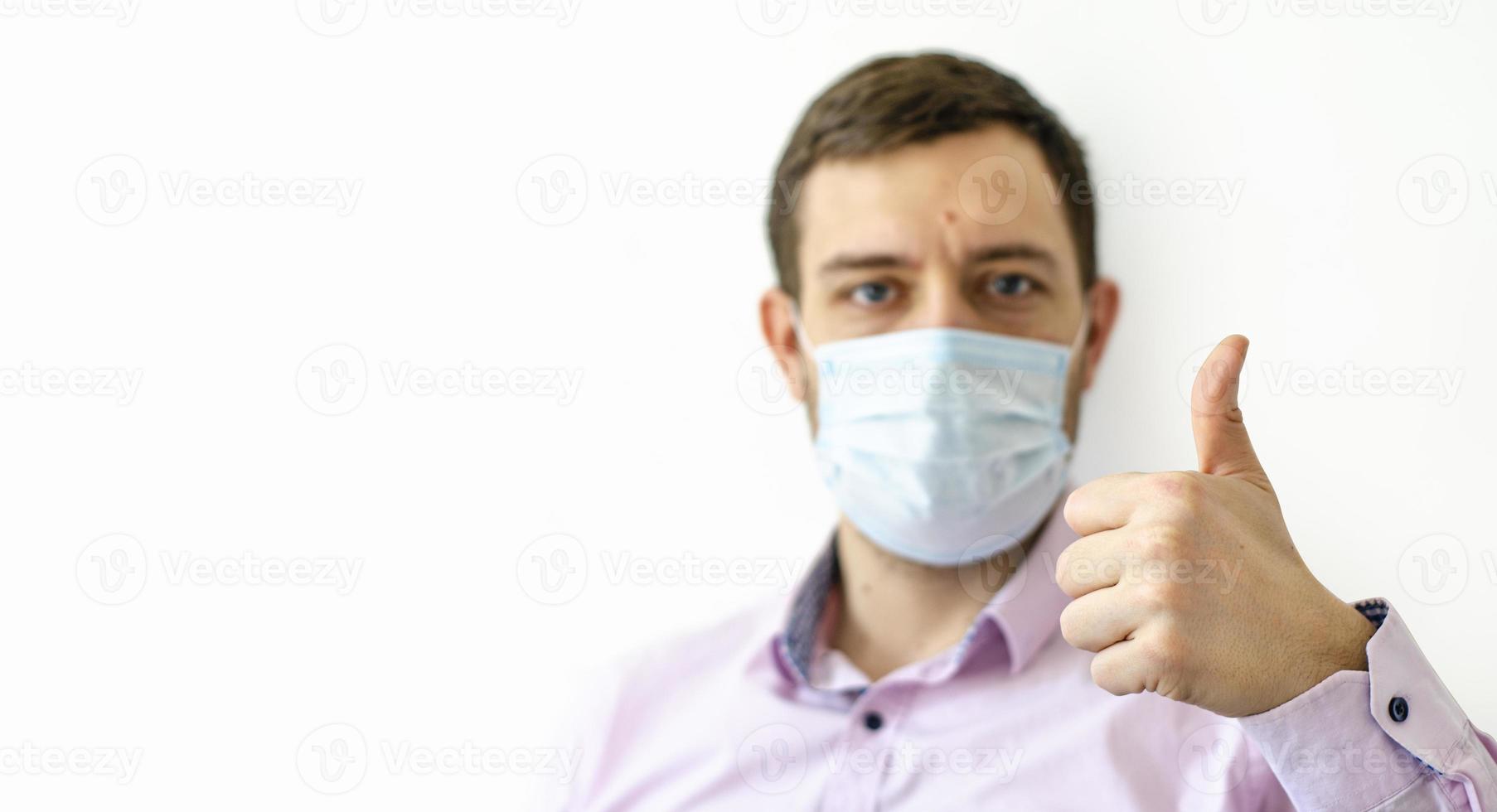 un uomo in camicia con una maschera protettiva. mostrando i pollici in su. foto