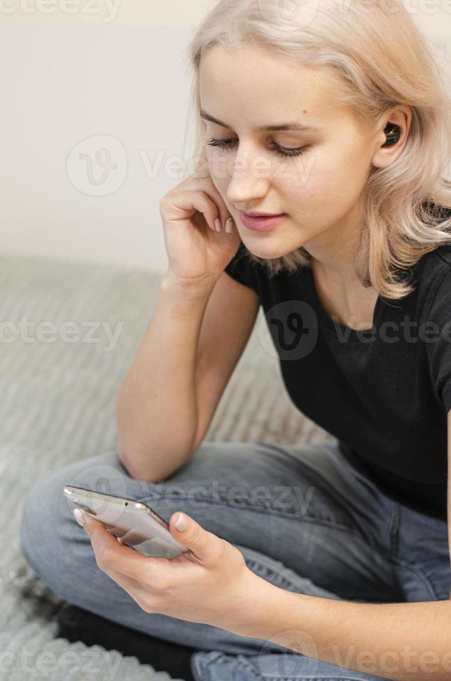 ragazza gode di musica in cuffie wireless. seleziona la musica sul telefono. foto