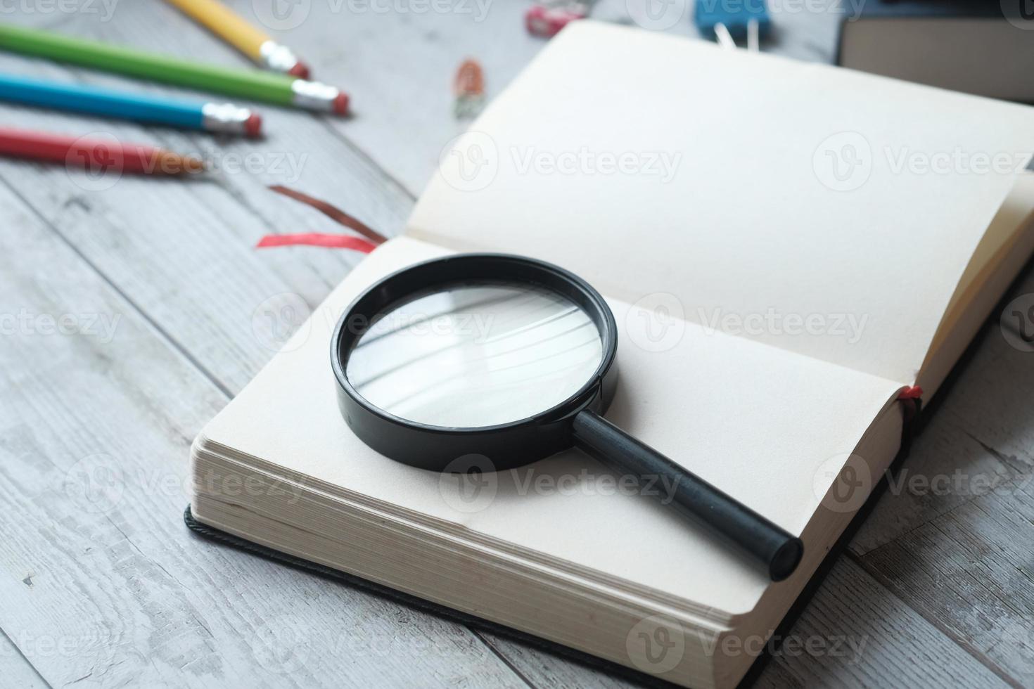 libro aperto e lente d'ingrandimento sul tavolo. foto