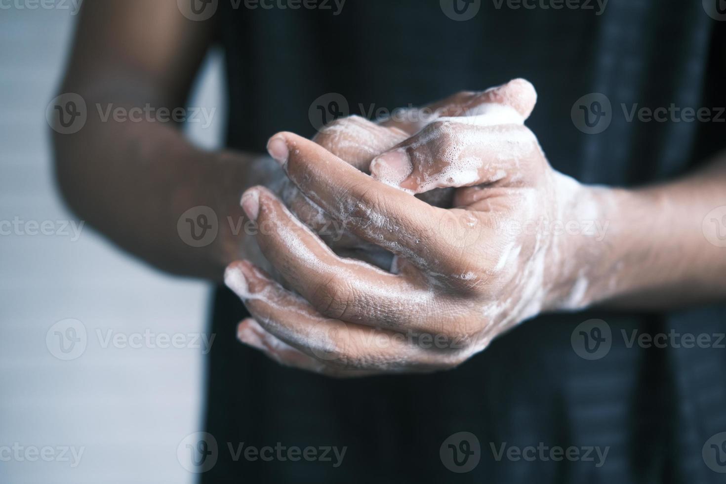 giovane che si lava le mani con acqua calda e sapone foto