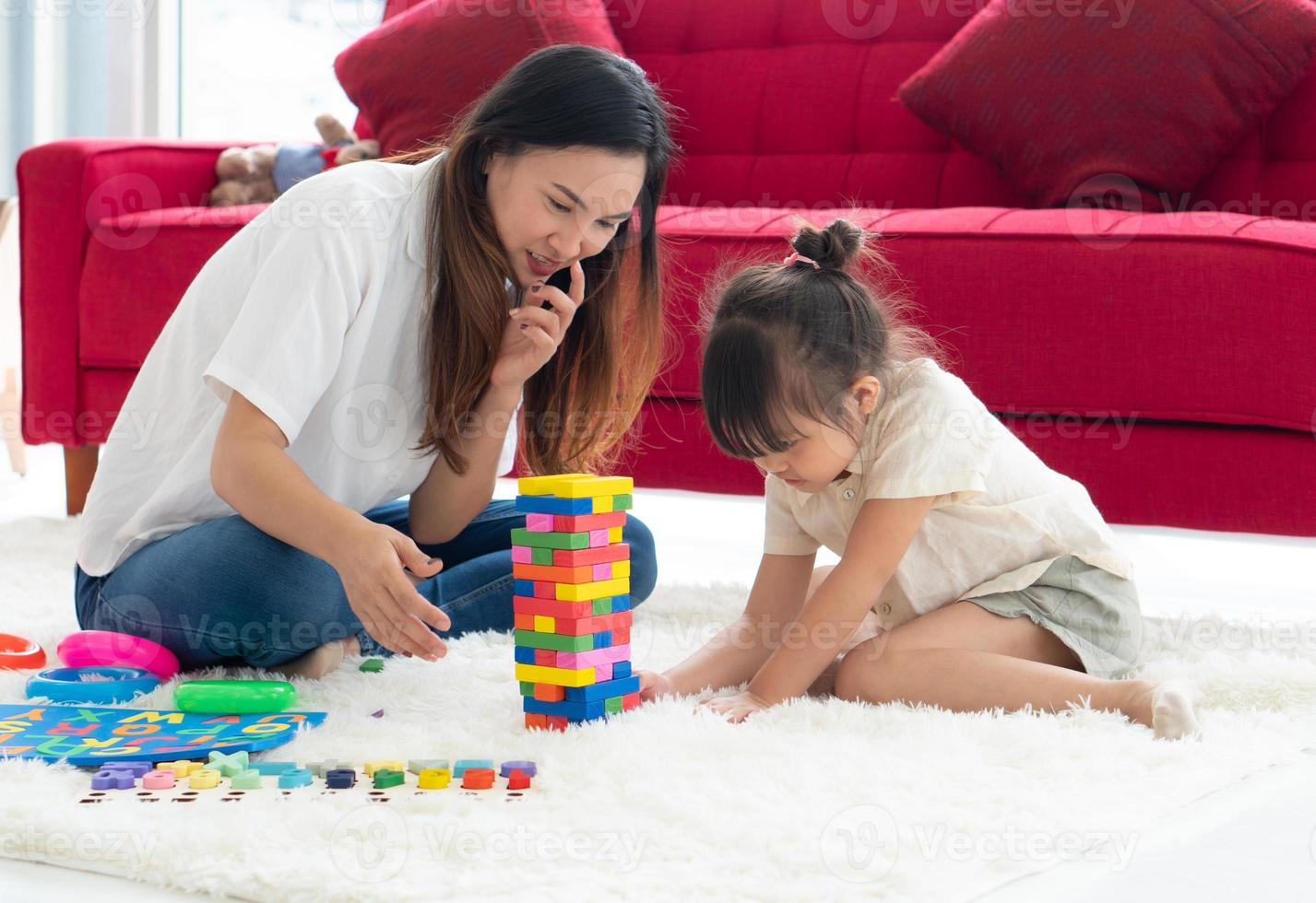 madre asiatica che insegna alla sua giovane figlia a giocare a puzzle a casa foto