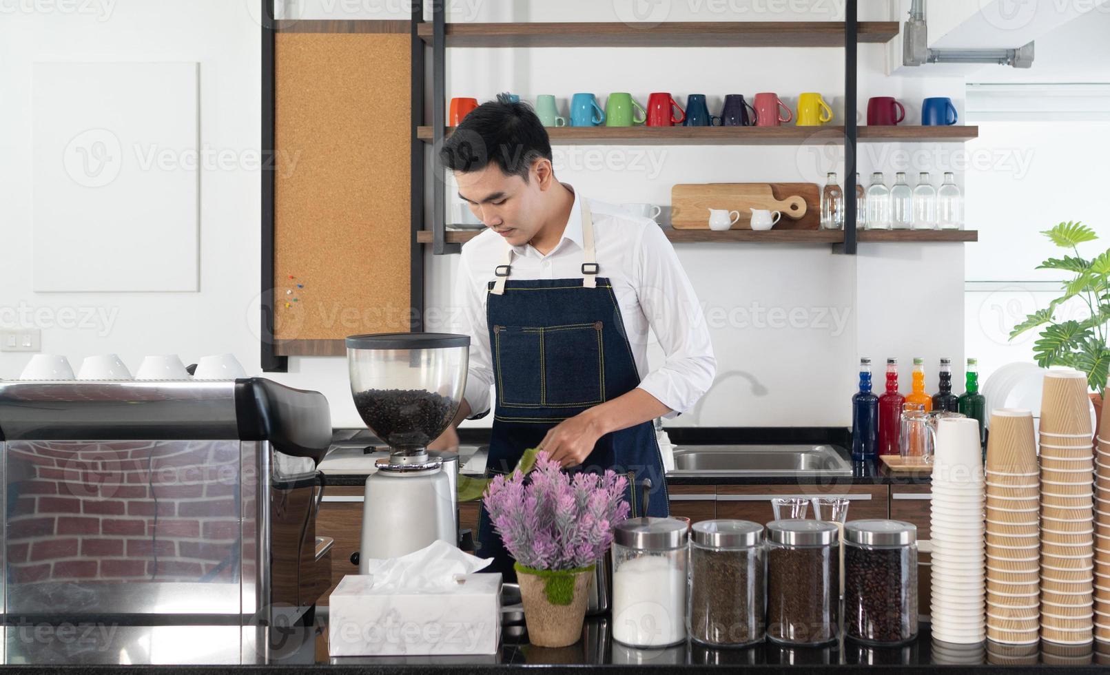 giovane barista asiatico che usa la caffettiera per preparare l'espresso nella caffetteria foto