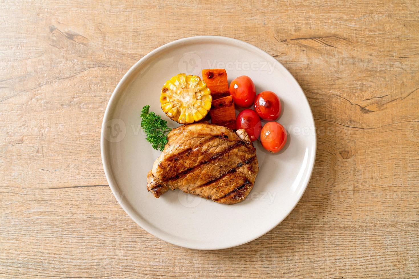 Filetto di maiale alla griglia e barbecue con mais, carota e pomodori foto