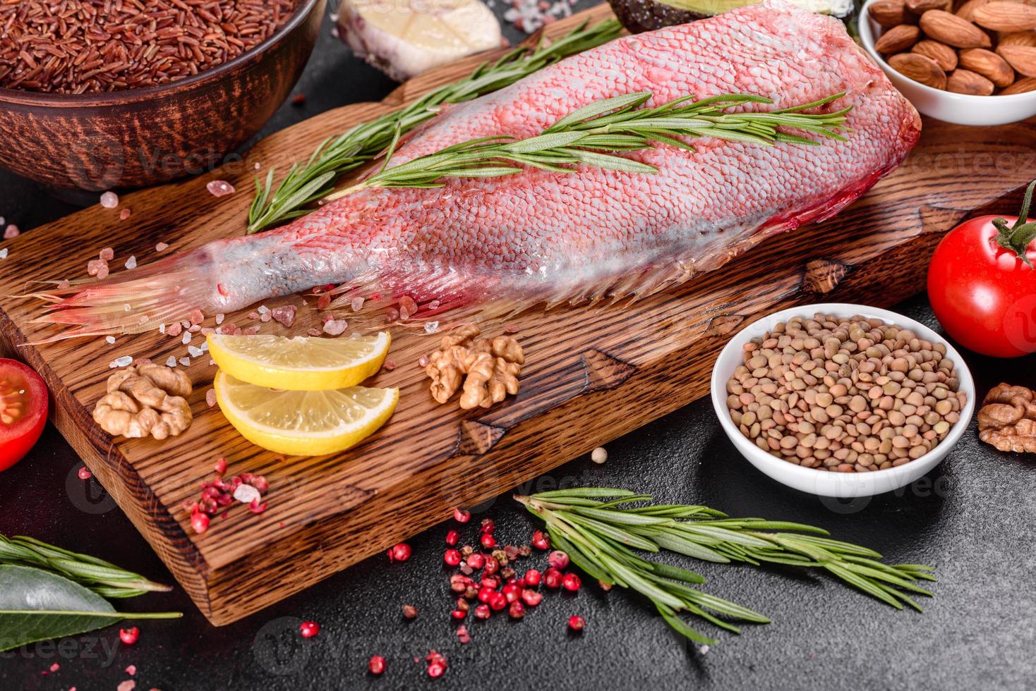 filetto crudo di pesce persico rosso preparato per la cottura con spezie ed erbe aromatiche foto