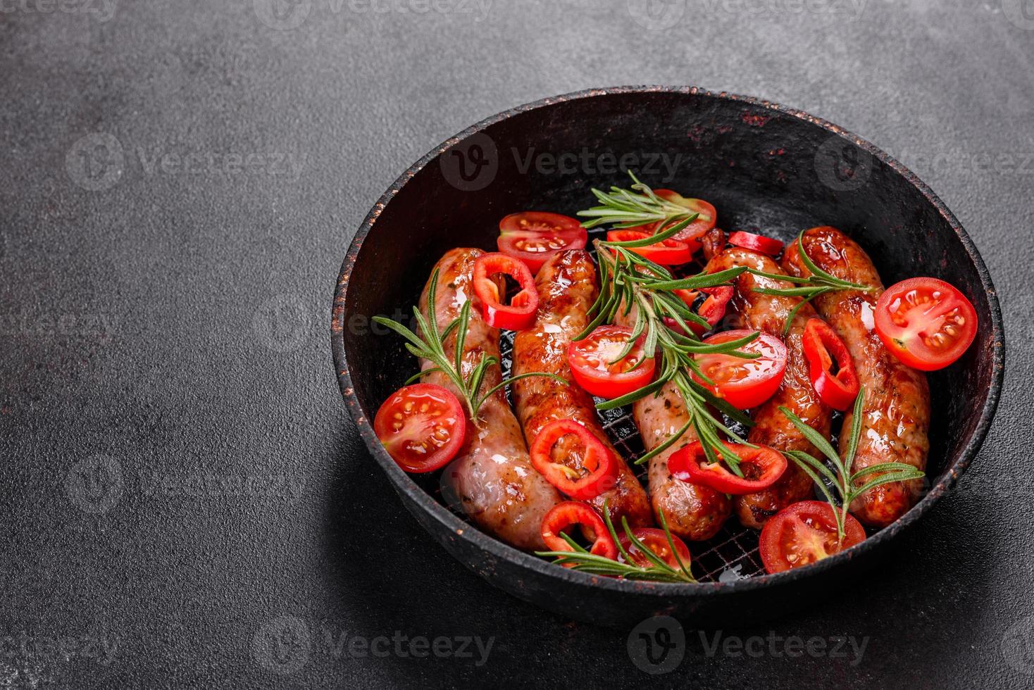 salsicce alla griglia con verdure e spezie su sfondo nero foto