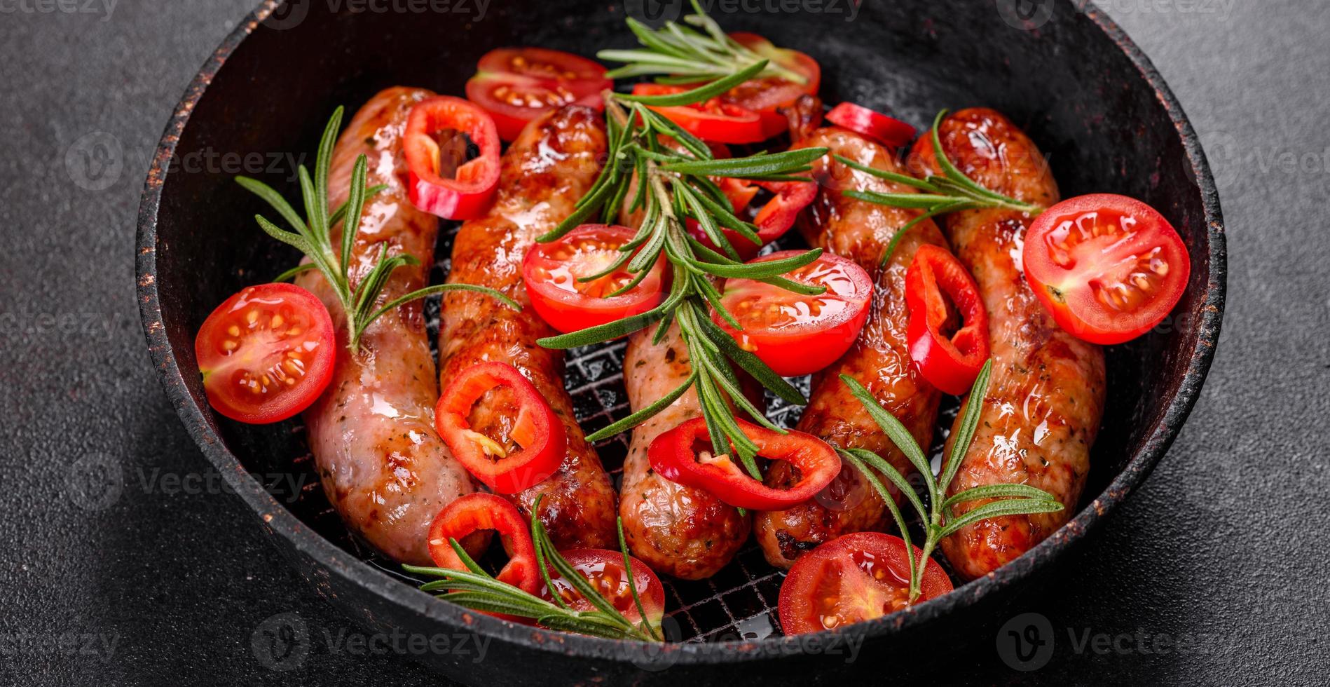 salsicce alla griglia con verdure e spezie su sfondo nero foto